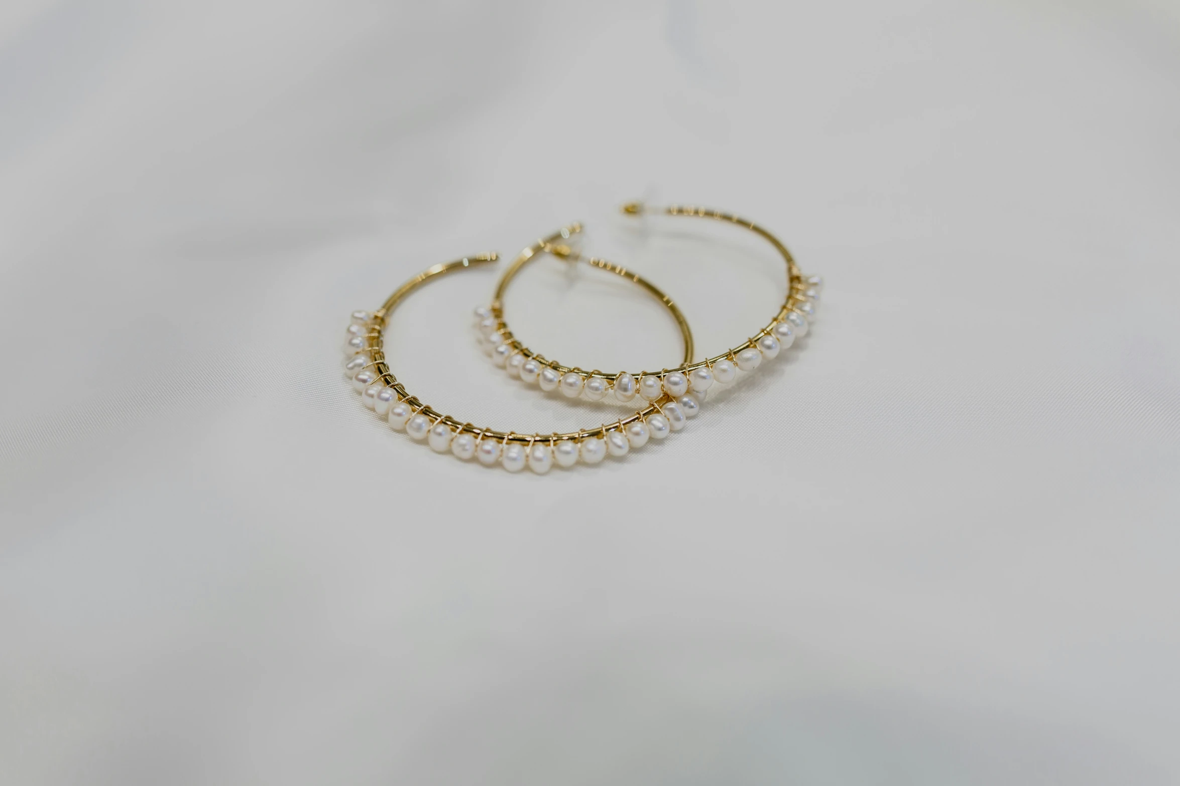 two gold hoop earrings are stacked high on top of each other