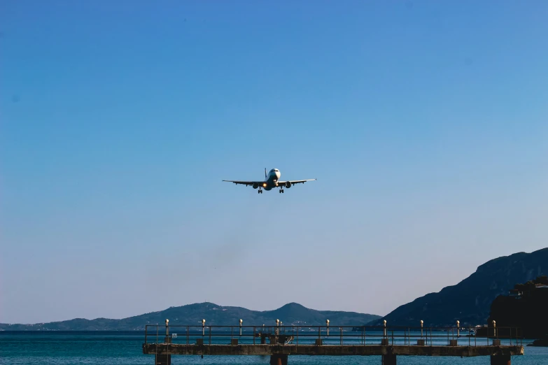 a plane is flying over the water with mountains in the background