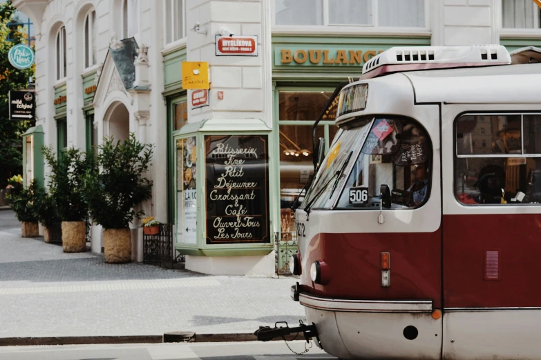 a red and white streetcar driving past a bakery