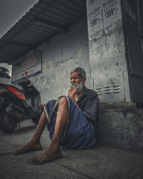 a man sitting on the ground next to a scooter