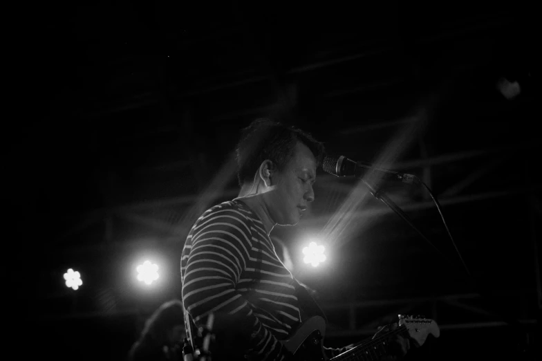 a man playing an electronic music instrument while lit by spotlights