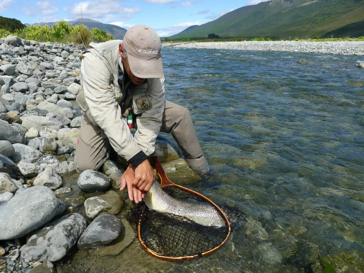 the man is crouched down and showing his fish