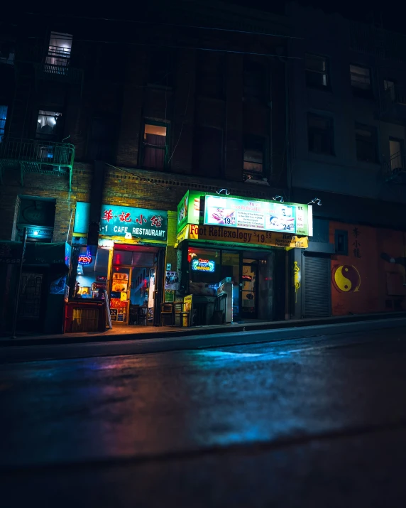 a dark street at night with a neon lit building and storefront