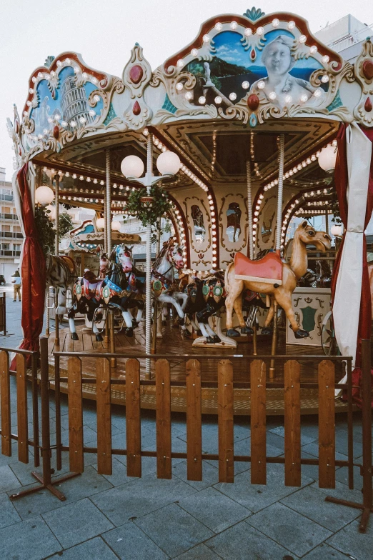 a carousel set up near a sidewalk with red and white curtains