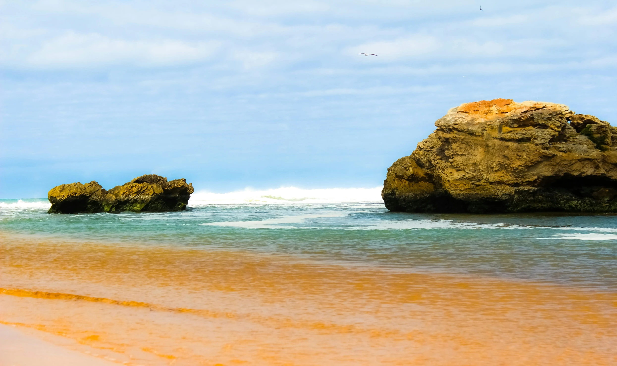 a couple of rocks on the shore of a beach