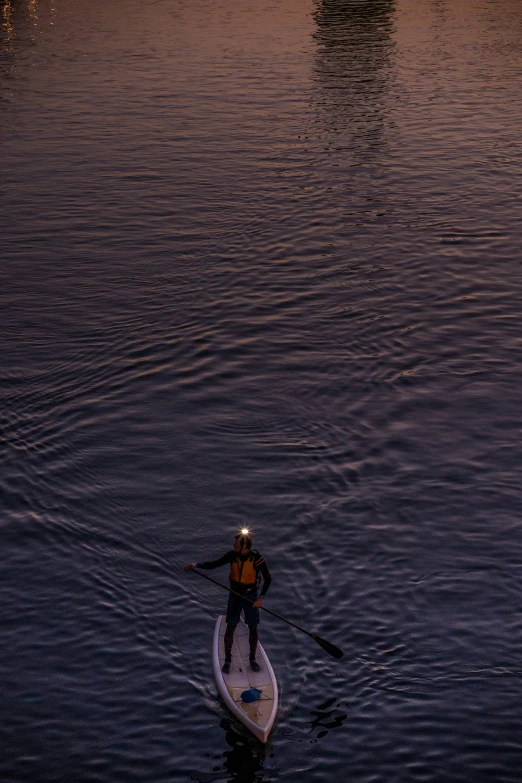 man on paddle board in front of the setting sun