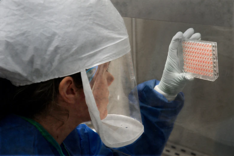 woman wearing medical clothing holding up a toothbrush to use it