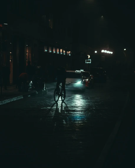 a person riding a bike at night on a wet street