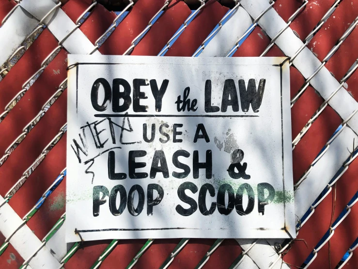 a sign hanging on a fence that says obey the law