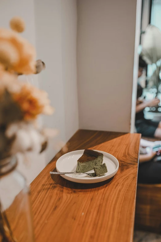 a slice of dessert sitting on a plate next to a woman