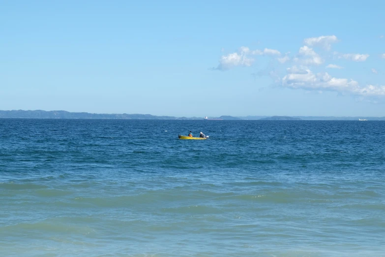 people in yellow boats on the ocean with mountains