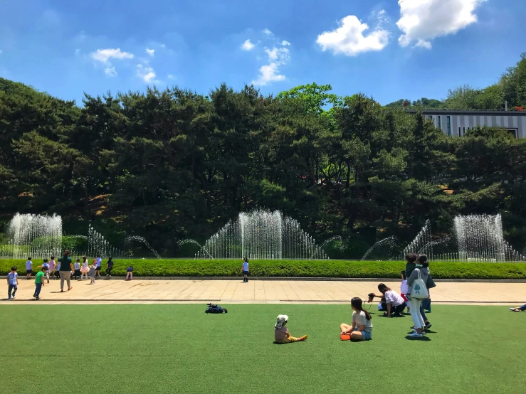 a few people sitting in the grass playing with a kite