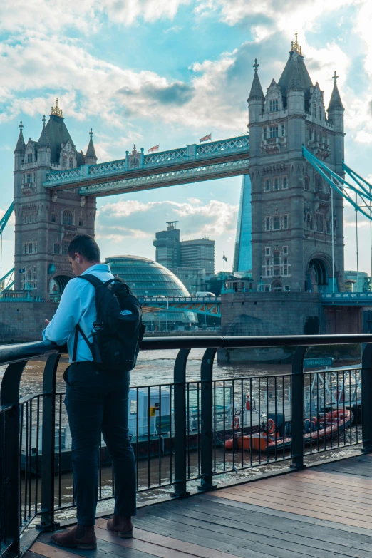 a man with a backpack standing on a bridge looking at the city