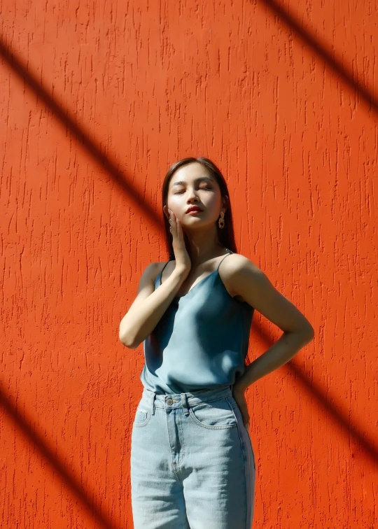 woman leaning on red wall posing for the camera