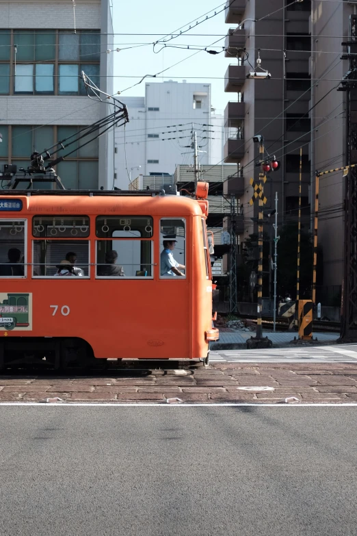 an orange trolley rides down a city street