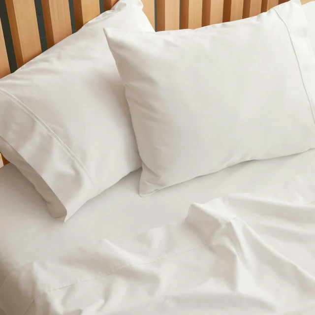 white pillows sitting on top of a bed next to sheets