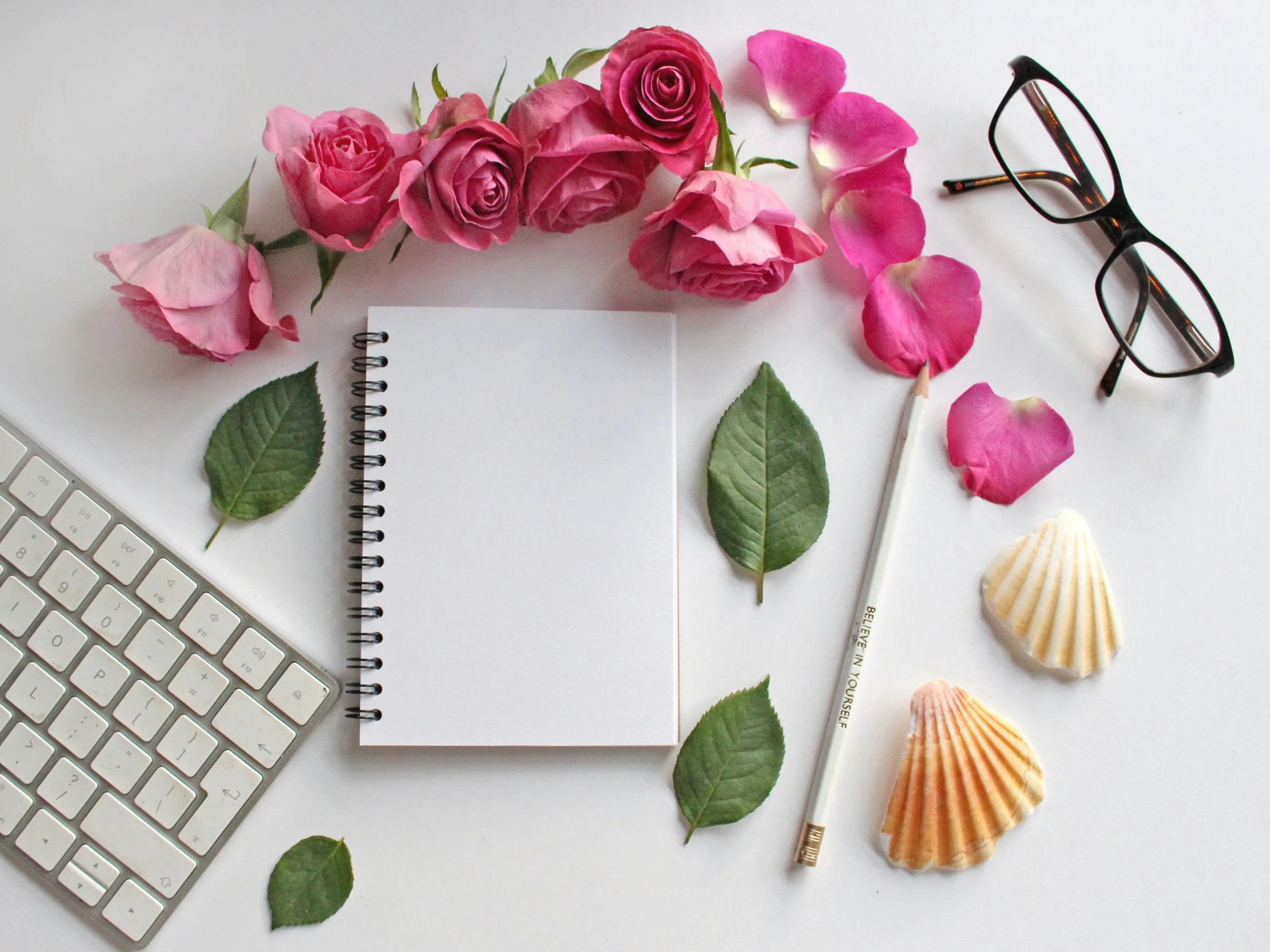 a notebook and flowers next to a keyboard