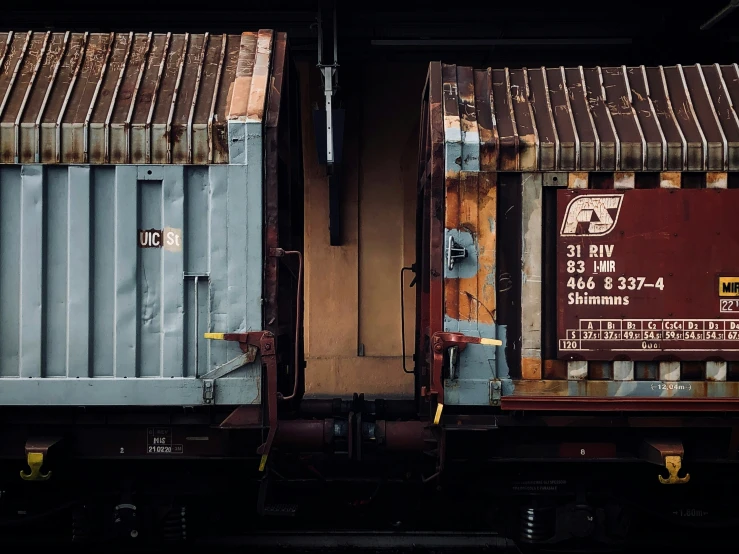 two rusted train cabooses sit together in front of a sign