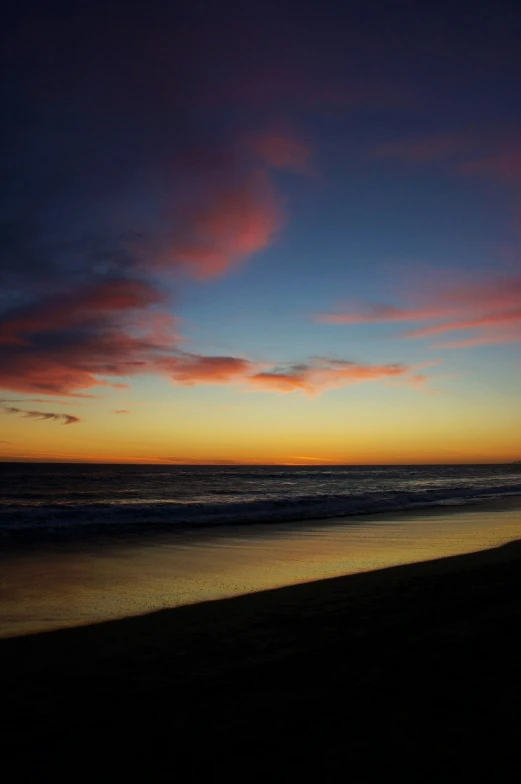 a person standing on the beach in front of a sunset