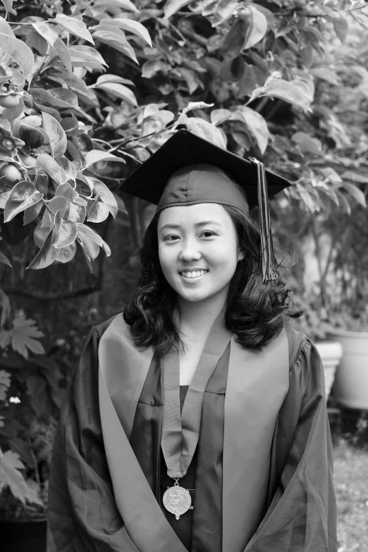 girl in her graduation cap and gown with tassel and flower