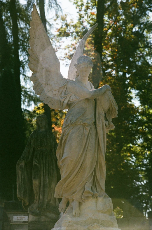 a statue with wings stands in a cemetery