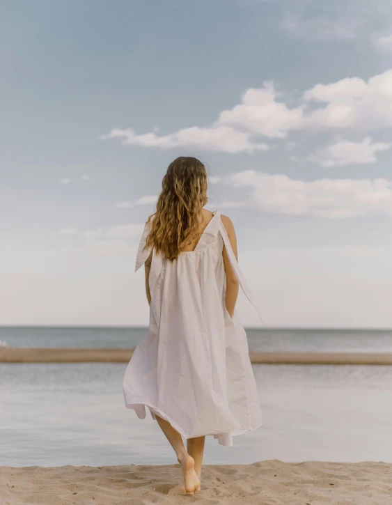 a young woman walking on the sand near water