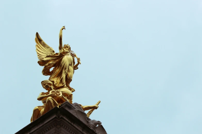 the golden angel statue atop a tower is flying