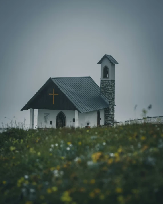 a church with a steeple sits on a hill near the grass