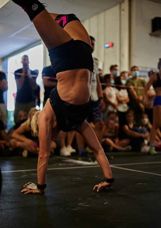 a woman in a black sports outfit is doing a handstand