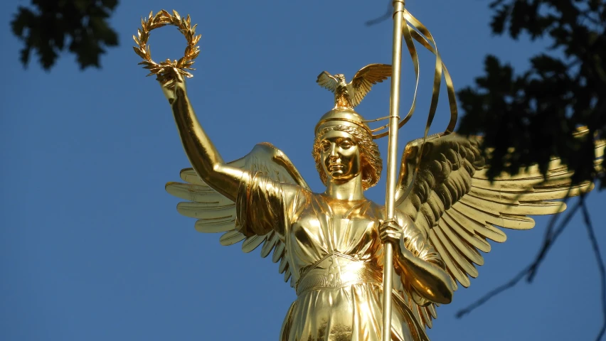 a gold angel statue is displayed on top of a tree