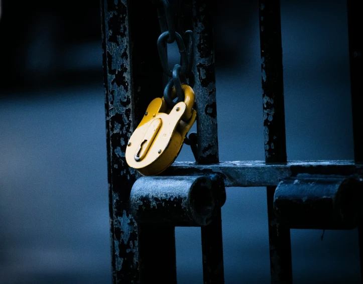 a close up of a metal gate with a lock and a yellow latch