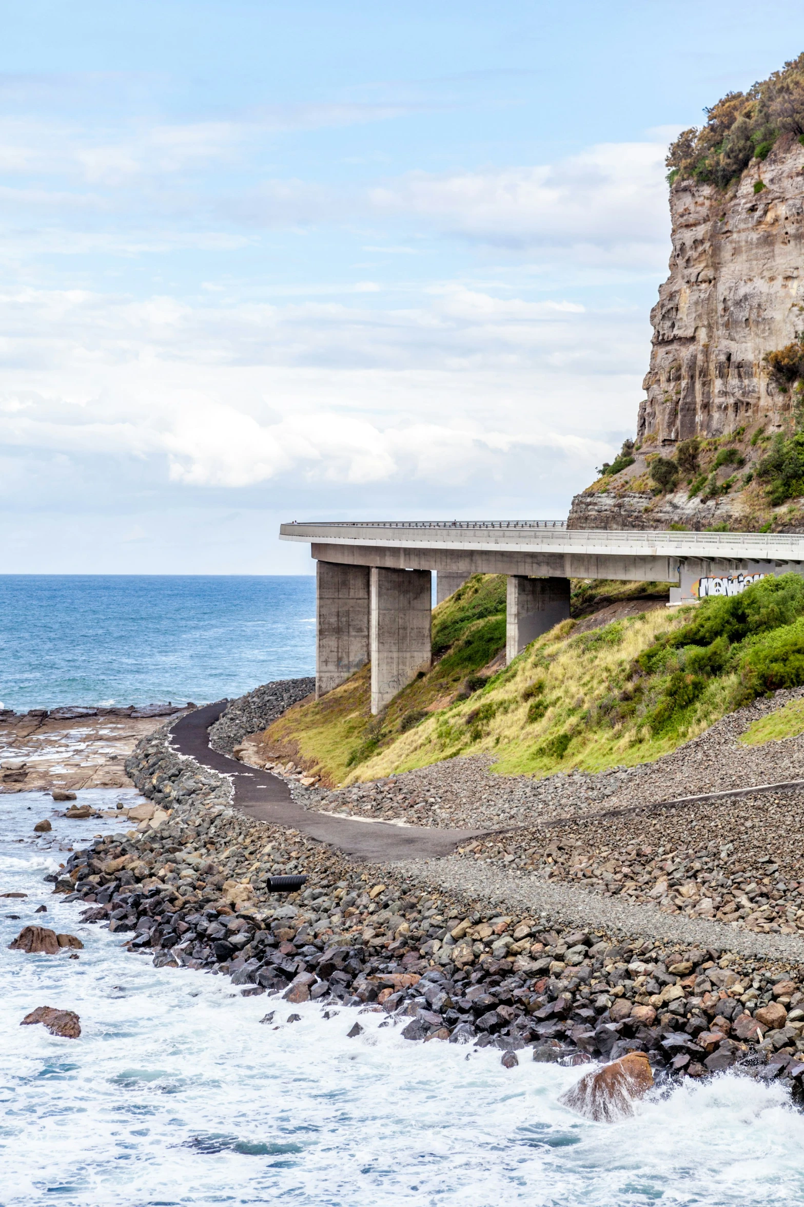 a highway overpass sits over a rock - bordered cliff