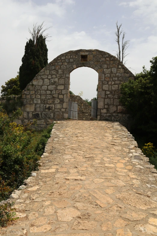 an empty, cobble stone path with a stone arch in it