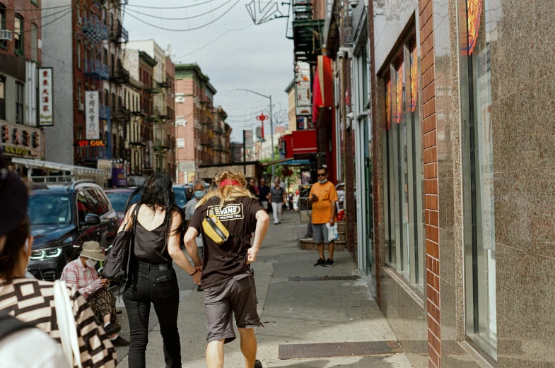 a group of people walking on a street next to tall buildings