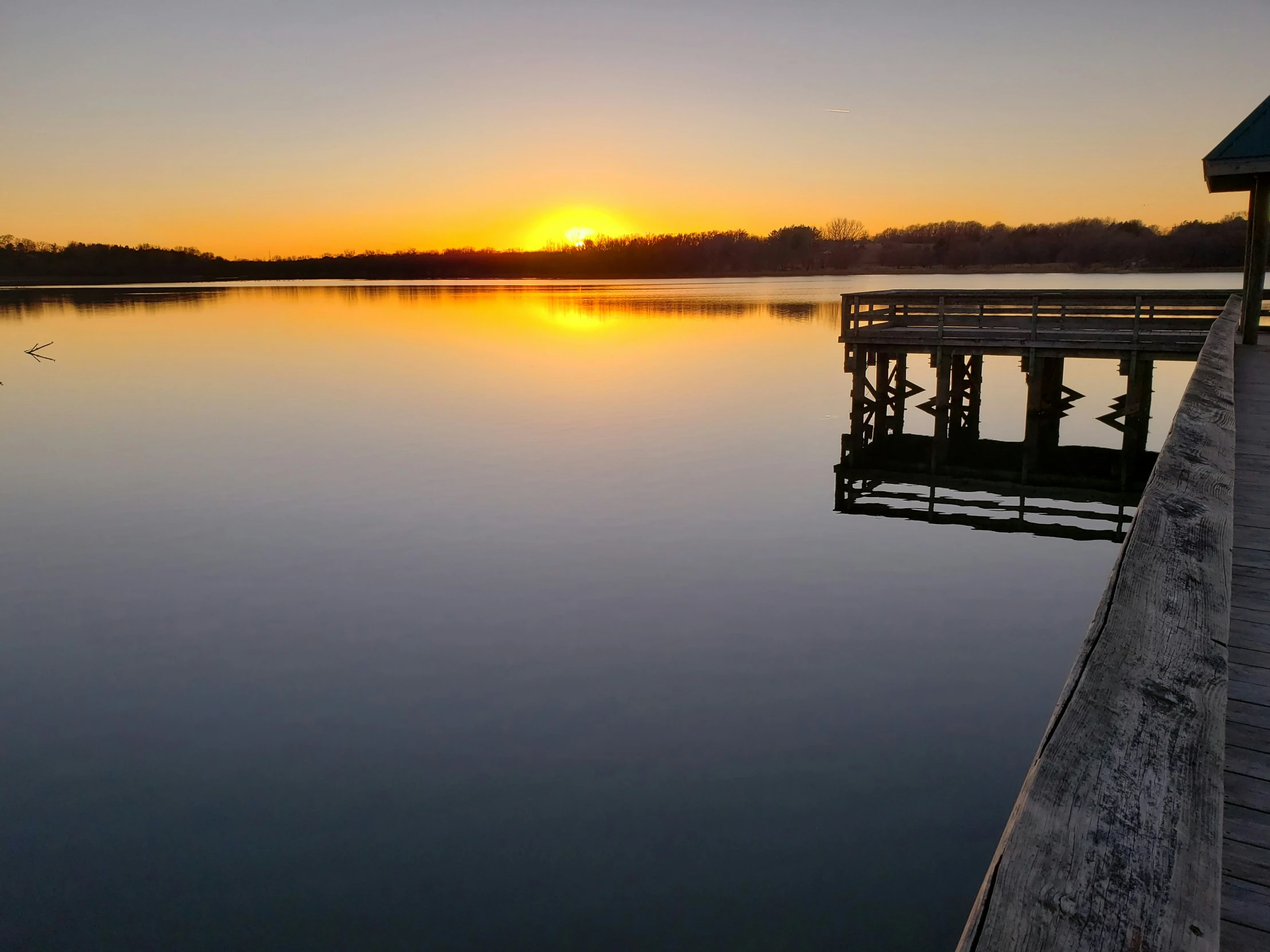 the sunset is reflected on the still water