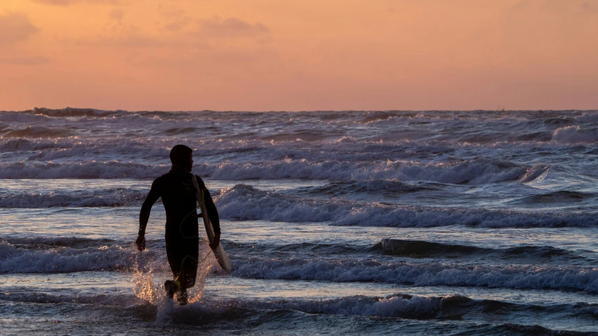 the person in the wet suit is walking through the ocean