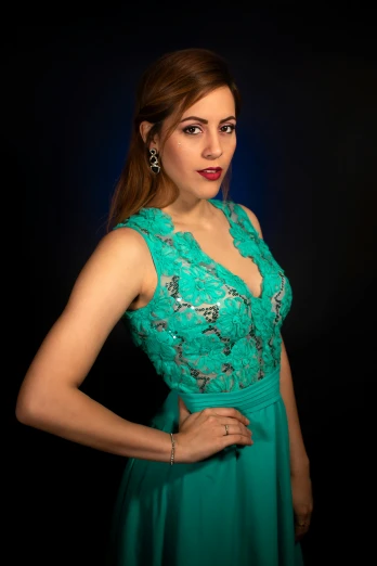 woman in turquoise dress posing on dark background
