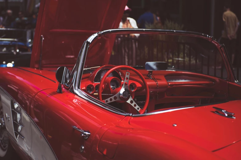 an image of a red convertible car inside a car show