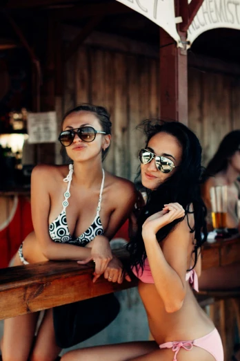 two women in bathing suits with glasses at a bar