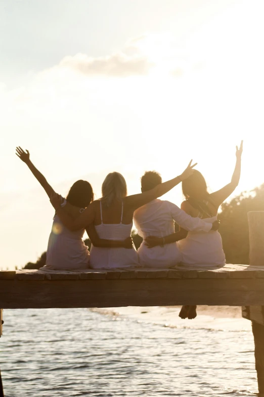 a group of girls sitting on top of a wooden dock