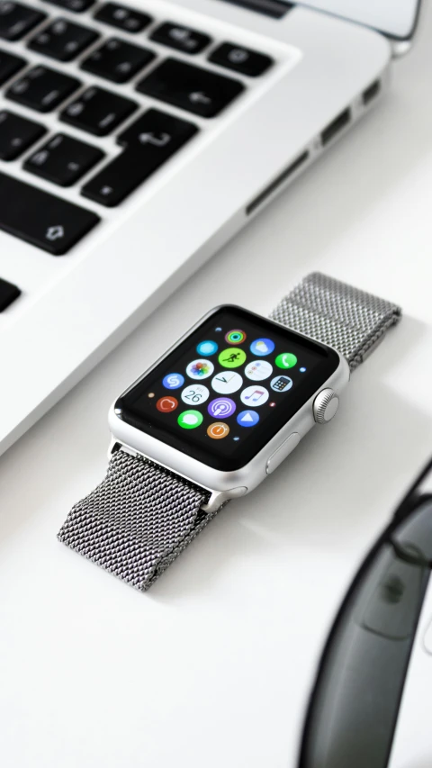 an apple watch on a computer desk with a keyboard nearby