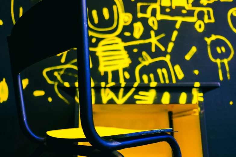 a chair is sitting in front of a black wall with bright yellow designs