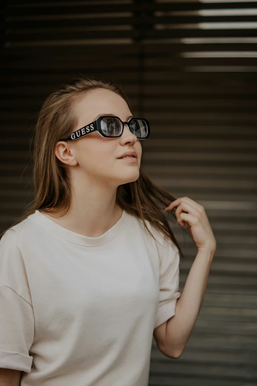 a woman with her sunglasses on smoking and standing near shutters