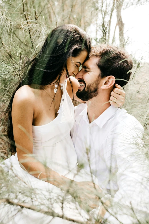 a young couple poses for their pograph in the woods