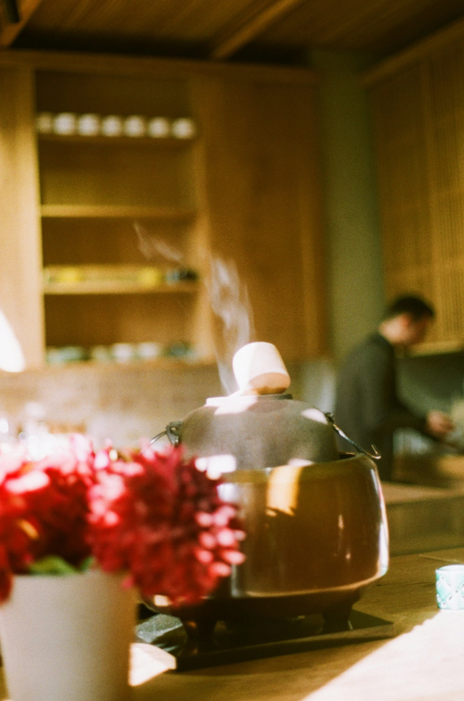 a tea kettle sitting on top of a counter next to a flower vase