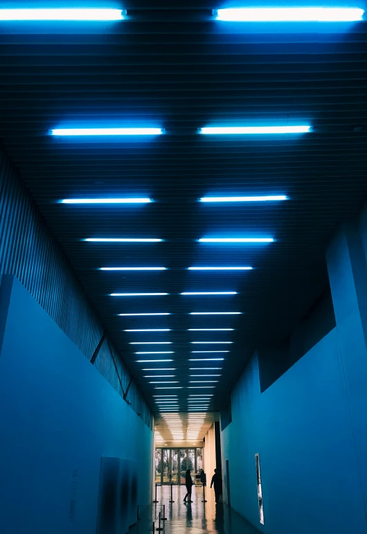 a long hallway with blue lights and a person walking down it