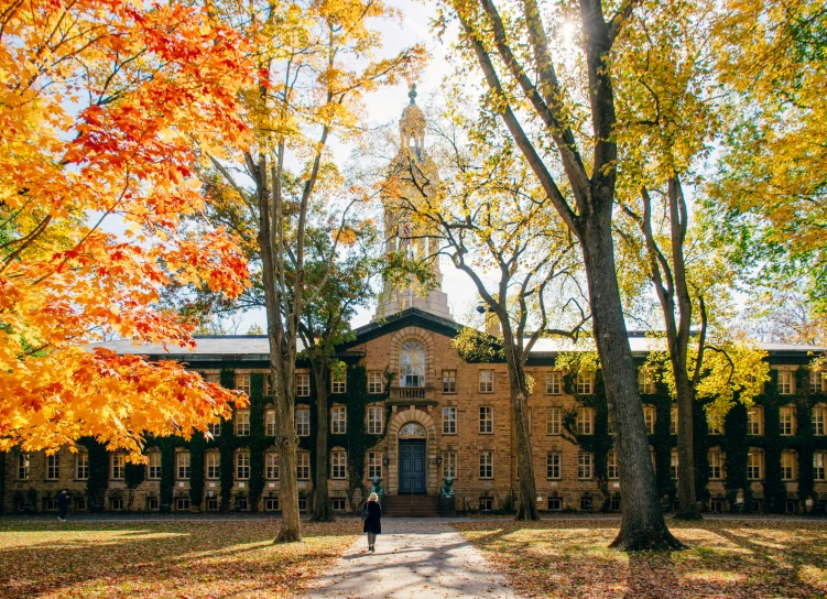 a man is walking through the leaves of fall in front of a building