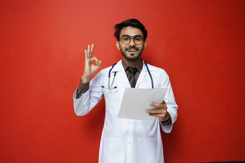 a male doctor holding up peace signs and holding a piece of paper