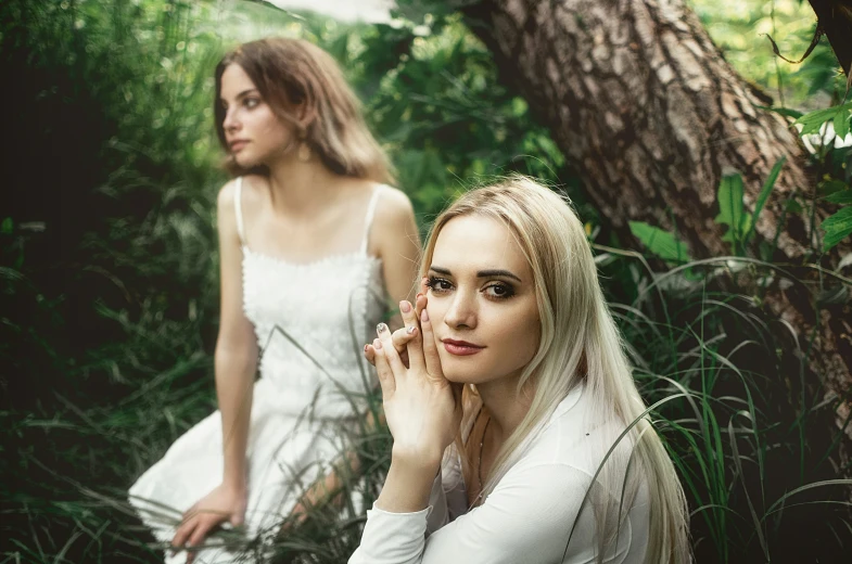 two women are sitting next to each other in the woods