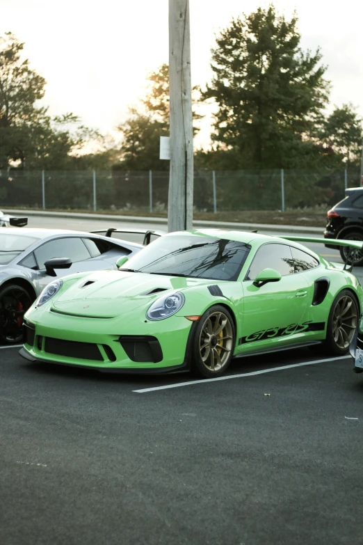 two green sports cars sit parked in a parking lot